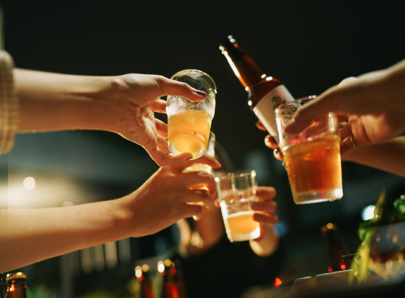 A group of people toasting beer glasses at a party.