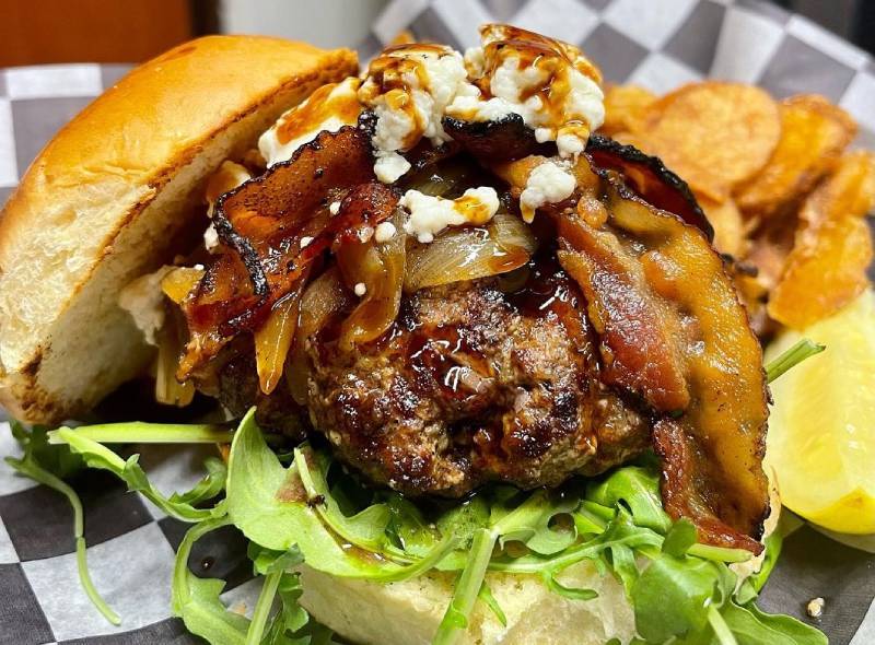 A burger with bacon and onions on it.